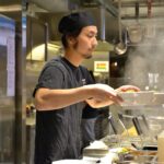 Cocinero japonés sirviendo un par de platos de ramen